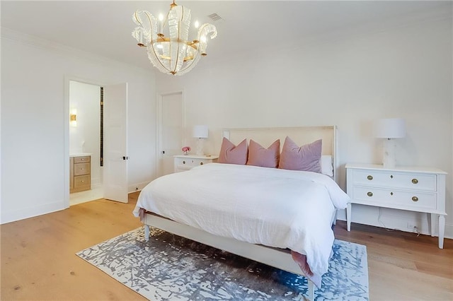 bedroom with ensuite bathroom, light hardwood / wood-style floors, crown molding, and a notable chandelier