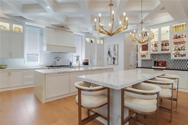 kitchen with pendant lighting, white cabinets, backsplash, a center island, and light hardwood / wood-style floors