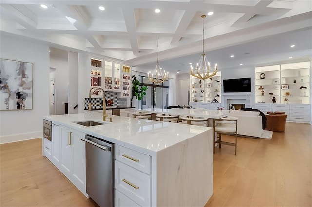 kitchen with white cabinets, sink, a spacious island, beam ceiling, and decorative light fixtures