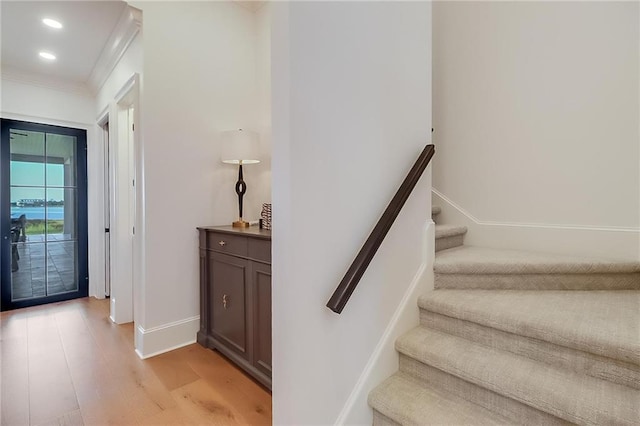 staircase with crown molding and wood-type flooring