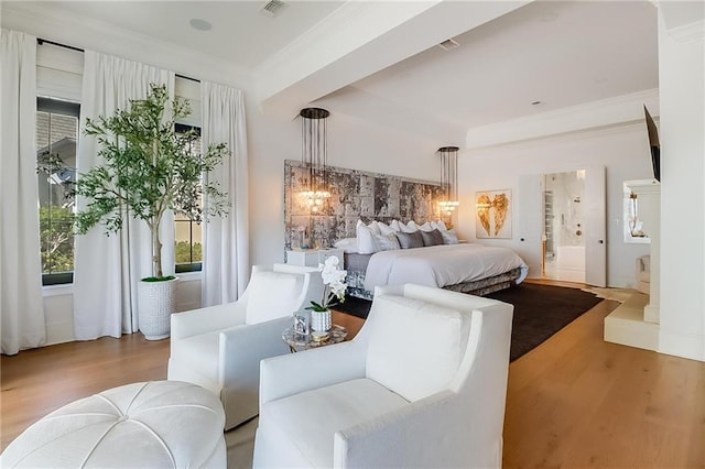 bedroom with light hardwood / wood-style floors, connected bathroom, and ornamental molding