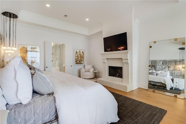 bedroom with ensuite bath, hardwood / wood-style floors, and crown molding