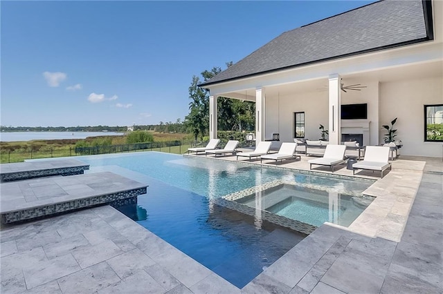 view of pool featuring ceiling fan, a patio, an in ground hot tub, and a water view