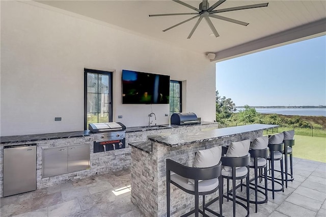 view of patio with exterior kitchen, a wet bar, area for grilling, and ceiling fan