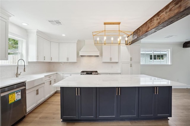 kitchen featuring stainless steel appliances, premium range hood, sink, white cabinetry, and decorative light fixtures