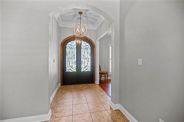 entryway with french doors, light tile patterned floors, a notable chandelier, and ornamental molding