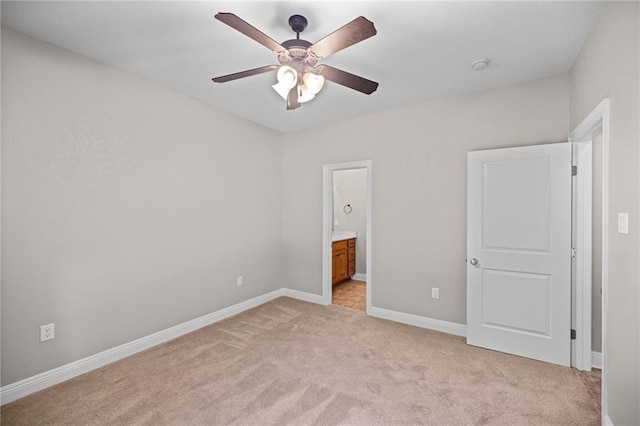 unfurnished bedroom featuring light colored carpet, ensuite bath, and ceiling fan