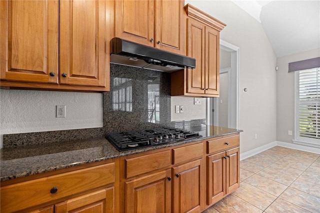 kitchen featuring tasteful backsplash, dark stone countertops, black gas stovetop, and vaulted ceiling