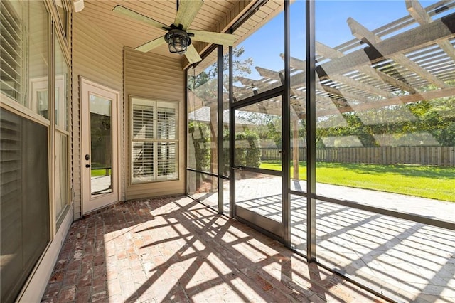 unfurnished sunroom featuring ceiling fan, vaulted ceiling, and a wealth of natural light