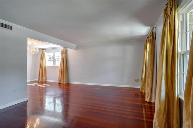 spare room with ornamental molding, a notable chandelier, and dark hardwood / wood-style flooring