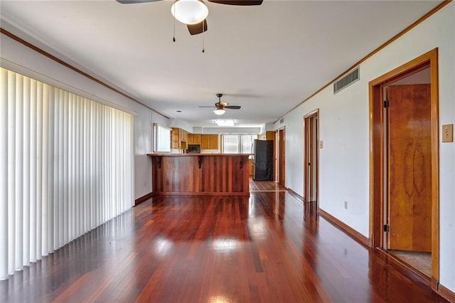 unfurnished living room featuring crown molding, ceiling fan, and dark hardwood / wood-style floors