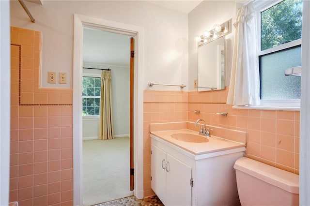 bathroom with toilet, a wealth of natural light, tile walls, and vanity