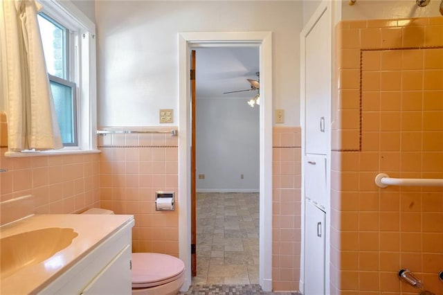 bathroom featuring ceiling fan, vanity, tile walls, and toilet