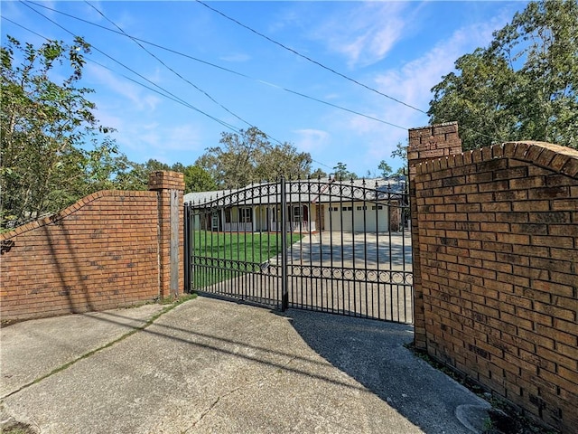 view of gate featuring a lawn and a garage