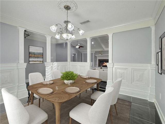 dining area featuring dark tile patterned flooring, ceiling fan with notable chandelier, ornamental molding, and decorative columns