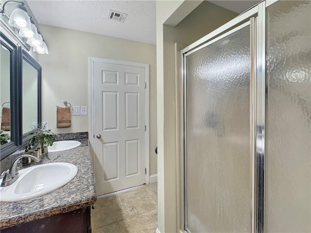 bathroom featuring a shower with door, vanity, and a textured ceiling