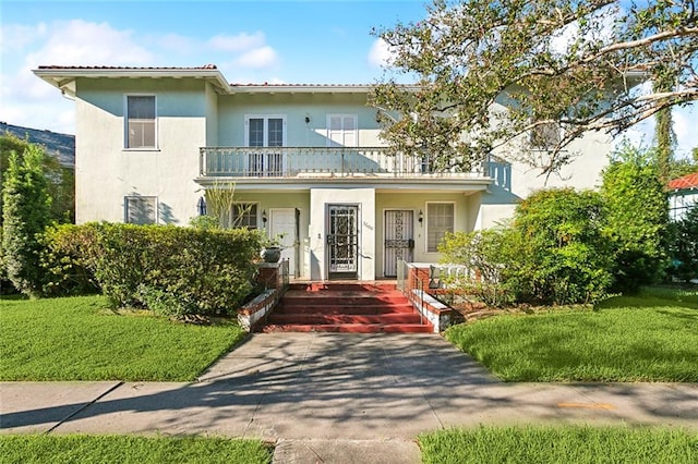 view of front of property featuring a balcony, a front lawn, and covered porch