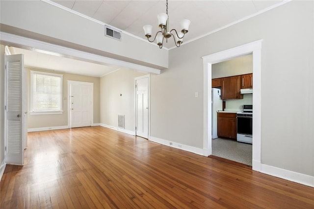 interior space with hardwood / wood-style flooring, crown molding, and an inviting chandelier