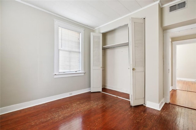 unfurnished bedroom with a closet, crown molding, and dark hardwood / wood-style flooring