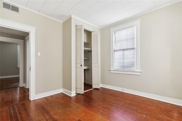 unfurnished bedroom with dark wood-type flooring, a closet, and crown molding