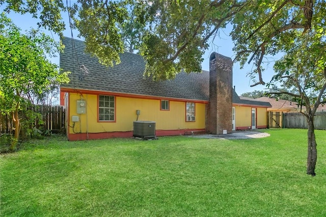 back of property with a patio, a yard, and central AC