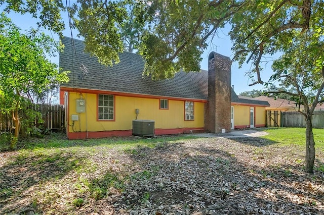 rear view of property featuring cooling unit and a lawn