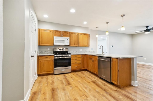 2109 Airline Park Blvd, Metairie, LA 70003 - kitchen featuring appliances with stainless steel finishes, a sink, light wood-type flooring, a peninsula, and baseboards