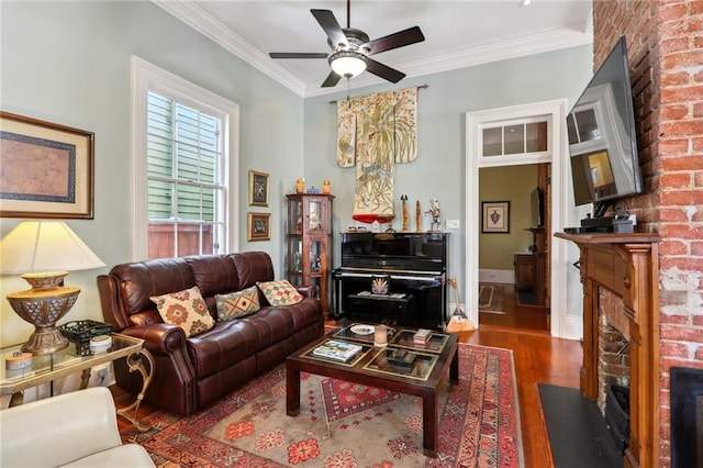 living room with a brick fireplace, dark hardwood / wood-style floors, ornamental molding, and ceiling fan