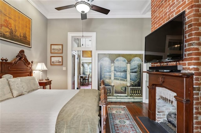 bedroom with ceiling fan, ornamental molding, a brick fireplace, and dark wood-type flooring