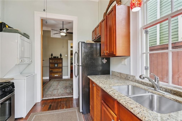 kitchen featuring stacked washer / dryer, sink, dark hardwood / wood-style flooring, and a healthy amount of sunlight