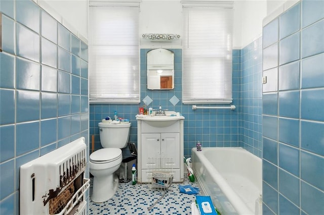 bathroom featuring vanity, toilet, a tub, tile walls, and tile patterned flooring