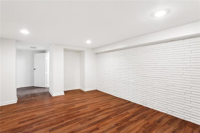 unfurnished room featuring dark hardwood / wood-style floors and brick wall