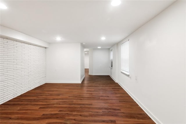 basement featuring dark hardwood / wood-style floors and brick wall