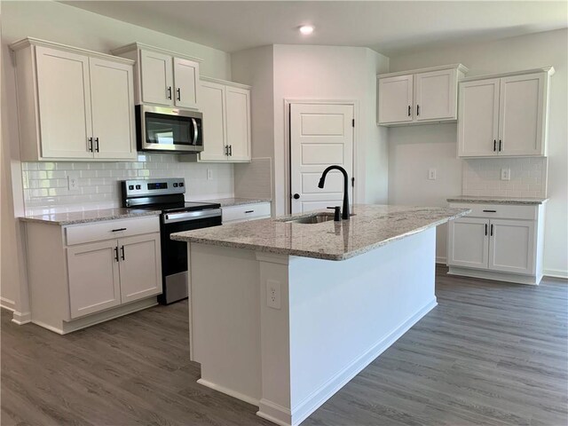 kitchen with appliances with stainless steel finishes, dark hardwood / wood-style flooring, sink, a center island with sink, and white cabinets