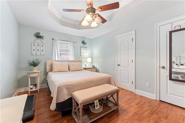 bedroom with a raised ceiling, wood-type flooring, crown molding, and ceiling fan