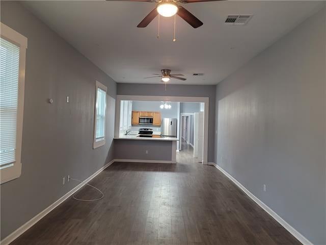 unfurnished living room with dark hardwood / wood-style flooring and ceiling fan