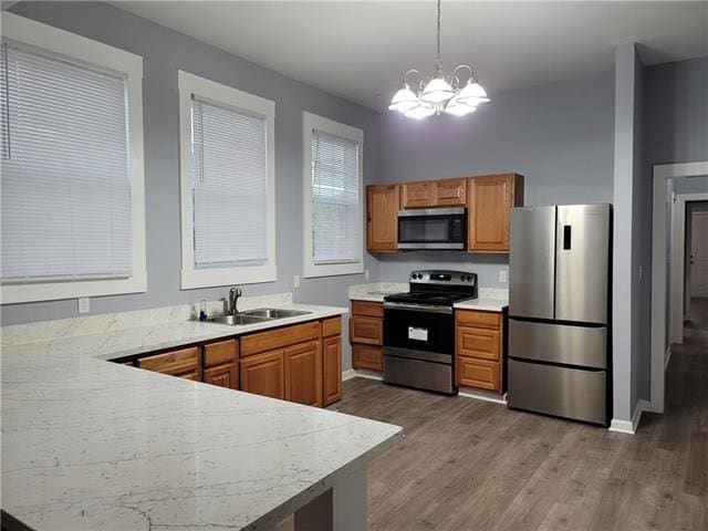 kitchen with pendant lighting, sink, a chandelier, appliances with stainless steel finishes, and dark hardwood / wood-style floors