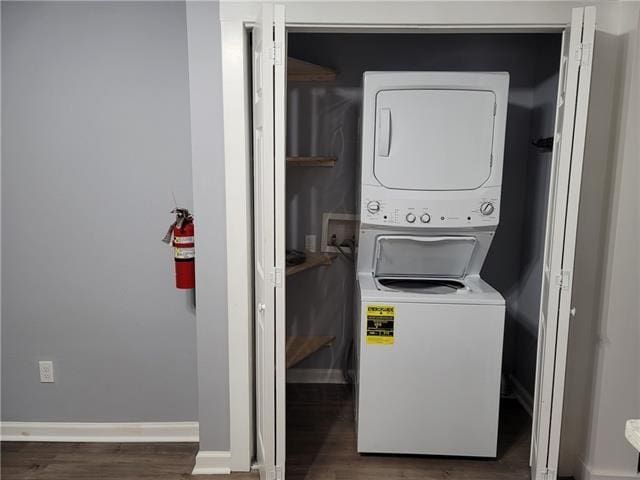 washroom with stacked washer and dryer and dark hardwood / wood-style flooring