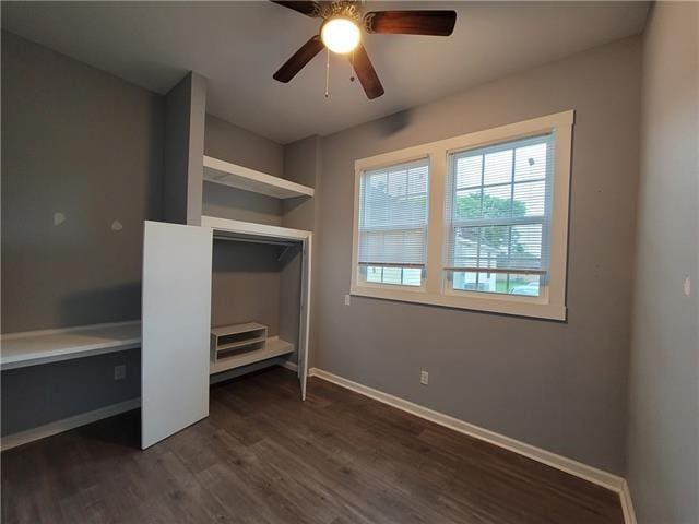 unfurnished bedroom featuring dark wood-type flooring, built in desk, and ceiling fan