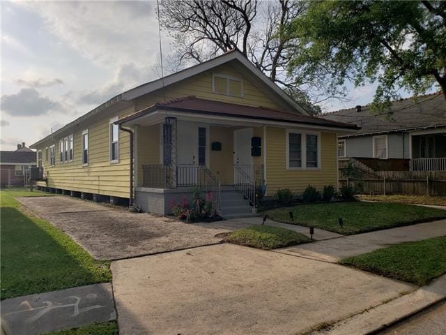 bungalow-style house with a front lawn and covered porch