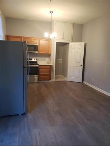 kitchen featuring appliances with stainless steel finishes, hanging light fixtures, and dark hardwood / wood-style flooring