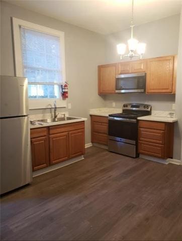 kitchen featuring pendant lighting, sink, a chandelier, stainless steel appliances, and dark hardwood / wood-style floors