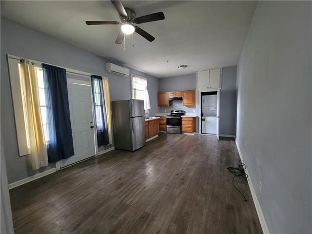 kitchen with appliances with stainless steel finishes, ceiling fan, a wall mounted air conditioner, and dark hardwood / wood-style flooring