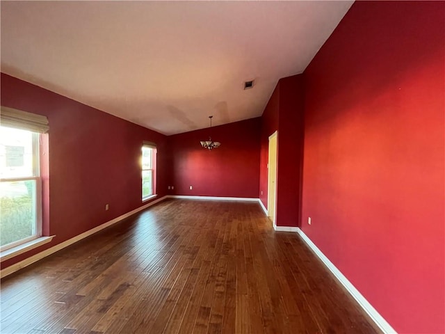 empty room featuring dark hardwood / wood-style flooring and a notable chandelier