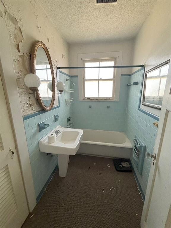 bathroom featuring tile walls, tiled shower / bath, and a textured ceiling