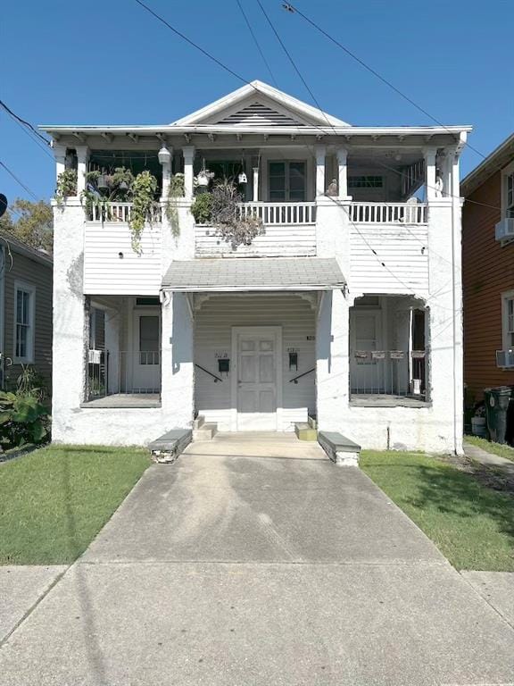 view of front of house with a balcony, a front yard, and a porch