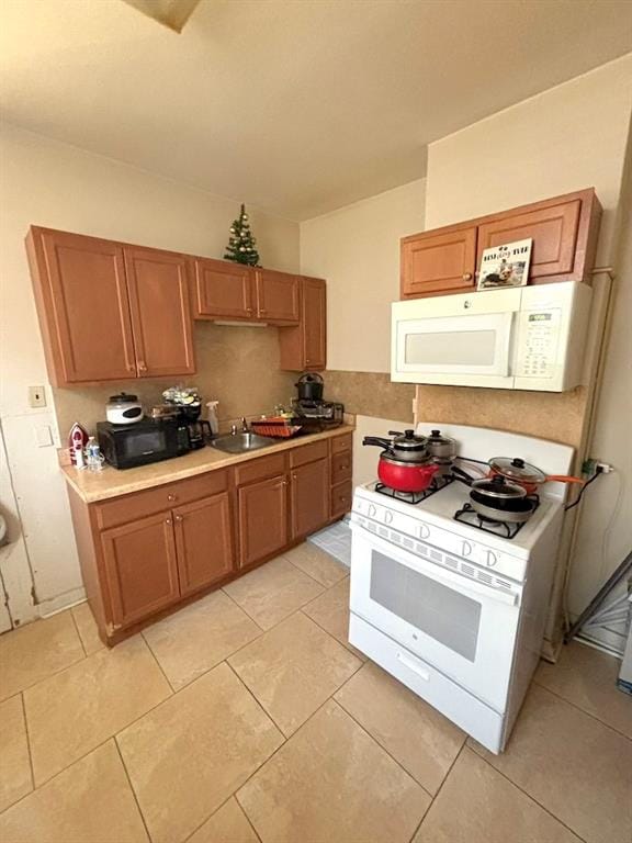 kitchen with light tile patterned floors, white appliances, and sink