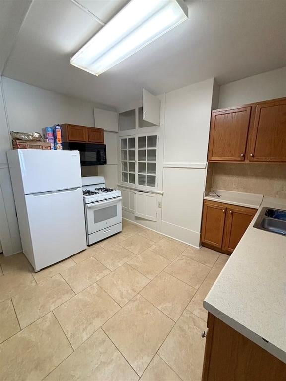 kitchen with white appliances, sink, and light tile patterned flooring