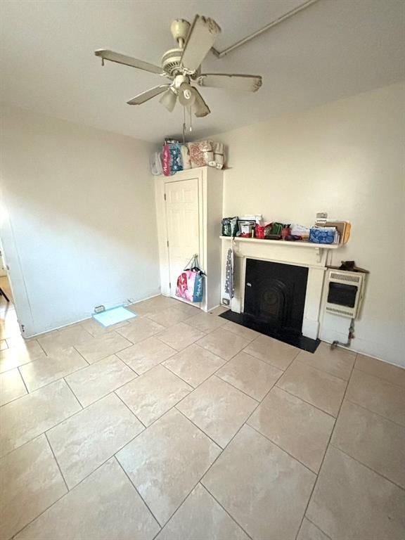 unfurnished living room with light tile patterned flooring, ceiling fan, and heating unit