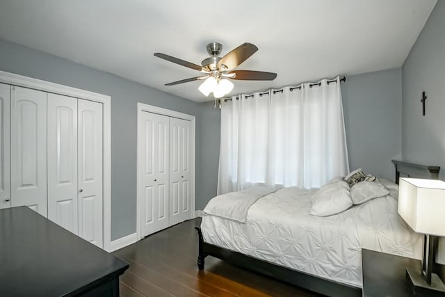 bedroom featuring ceiling fan, two closets, and dark hardwood / wood-style flooring